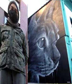 Xolaka delante de su mural del gato en Lugones 