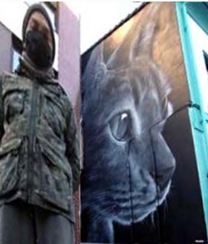 Xolaka delante de su mural del gato en Lugones  