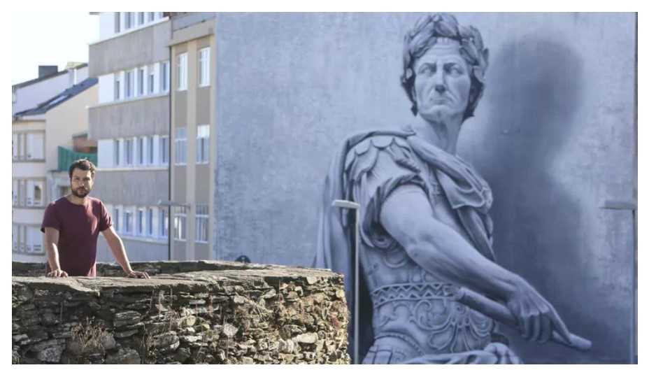 Diego As en la muralla romana frente a su mural  de Julio Cesar